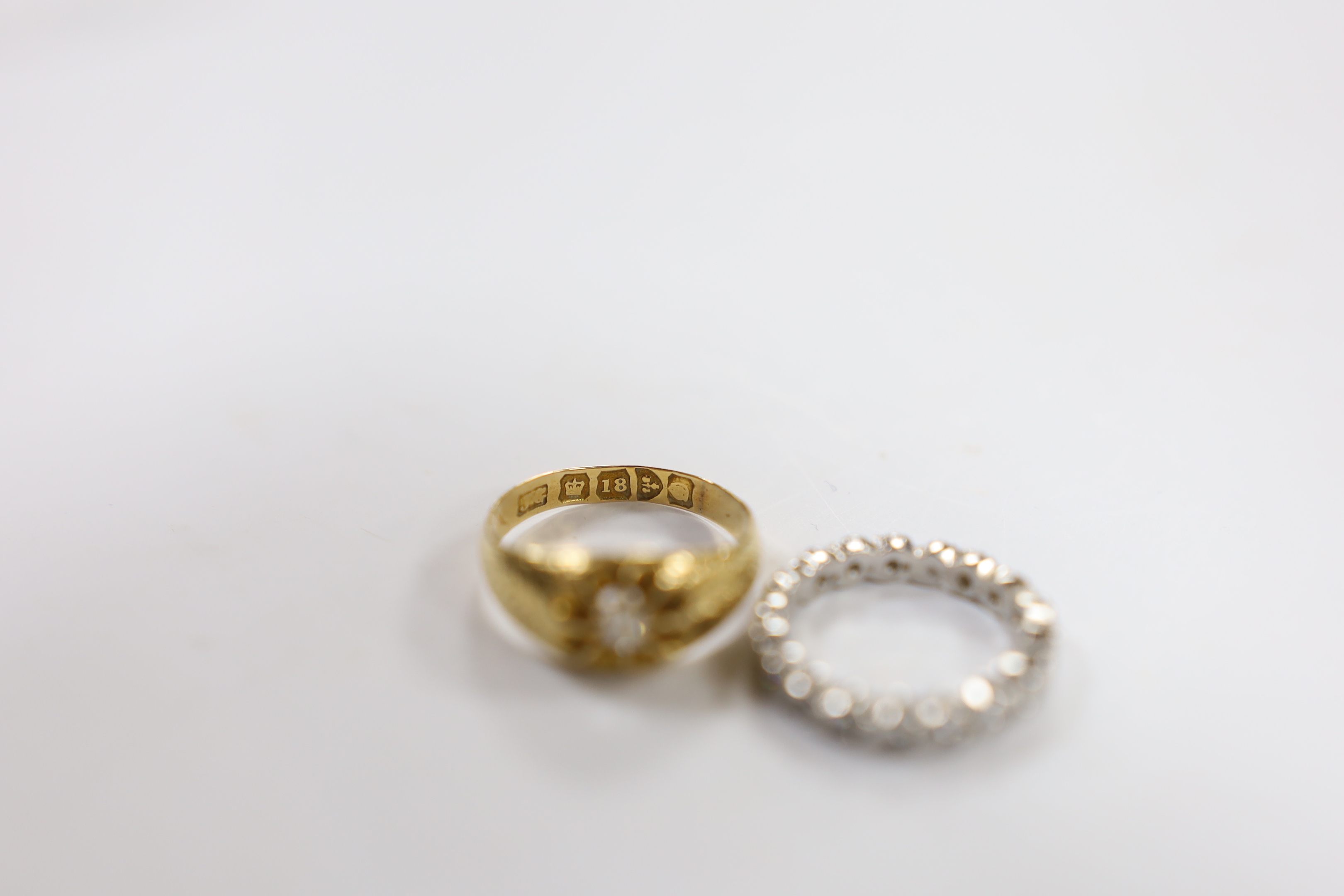 An early 20th century 18ct gold and claw set solitaire diamond ring, size M, gross 3.8 grams and a modern platinum and diamond chip set full eternity ring, size G, gross 3.1 grams.